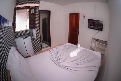 a white bed in a room with a mirror at HOTEL, RESTAURANTE E LANCHONETE PRIME in Valença