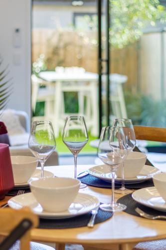 a wooden table with wine glasses and plates on it at Vibrant Central Christchurch Pad 2 bed 1 bath in Christchurch