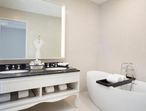 a bathroom with a tub and a sink and a mirror at Four Points by Sheraton Bandung in Bandung