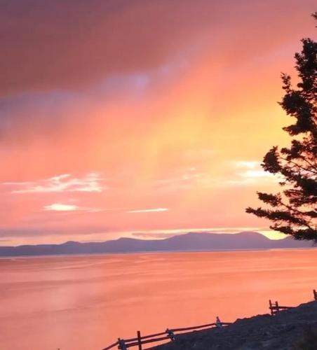 a sunset over a body of water with a fence at Le Martin Pecheur 2 à 4 personnes in Nouvelle