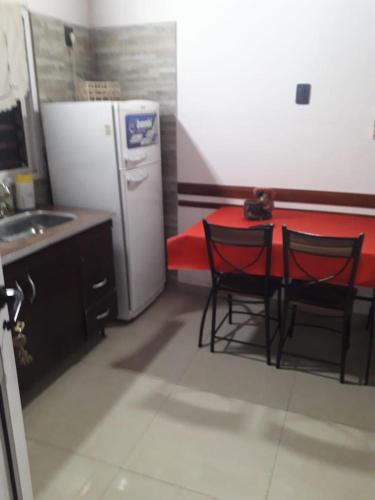 cocina con mesa, 2 sillas y nevera en Monoambiente hospital en Santa Teresita
