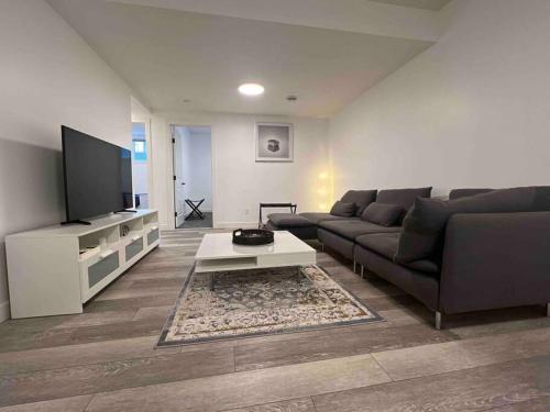 a living room with a couch and a tv at 2BR Suite, Private Entry, Full Kitchen, Washer & Dryer, Free Parking, Smart TV with Netflix, High-Speed Wi-Fi, Self Check-In, Near Banff National Park in Calgary