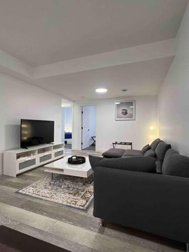 a living room with a black couch and a tv at 2BR Suite, Private Entry, Full Kitchen, Washer & Dryer, Free Parking, Smart TV with Netflix, High-Speed Wi-Fi, Self Check-In, Near Banff National Park in Calgary