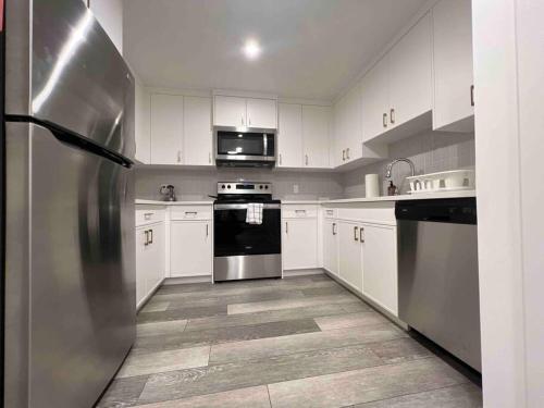 a stainless steel refrigerator in a kitchen with white cabinets at Cozy Retreat - Basement Hideaway - Closest to Banff in Calgary in Calgary