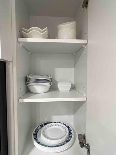 a white cabinet with plates and bowls on shelves at 2BR Suite, Private Entry, Full Kitchen, Washer & Dryer, Free Parking, Smart TV with Netflix, High-Speed Wi-Fi, Self Check-In, Near Banff National Park in Calgary