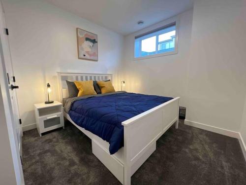 1 dormitorio con 1 cama con edredón azul y ventana en Cozy Retreat - Basement Hideaway - Closest to Banff in Calgary, en Calgary