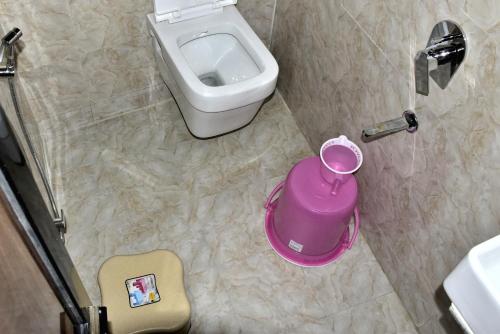 a small bathroom with a toilet and a pink trash can at ASRA DORMITORY For Male And Female in Mumbai