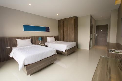 a bedroom with two beds with white sheets at V Hotel Ubon Ratchathani in Ubon Ratchathani