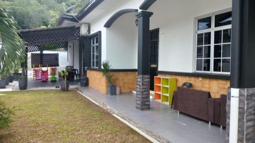 a house with a porch with a couch in the yard at Rosspine Homestay in Jitra
