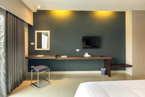 a bedroom with a desk and a tv on a wall at V Hotel Ubon Ratchathani in Ubon Ratchathani