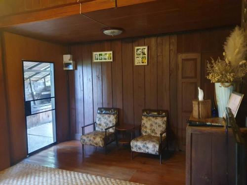 a living room with two chairs and a table at Kedthawa Homestay เฮือนเก็ดถะหวา in Ban Cho Lae