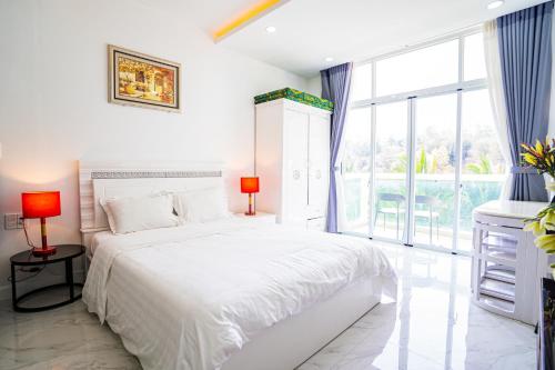 a white bedroom with a bed and a large window at Jack's Home - Ocean Vista Condotel Sealink Mui Ne in Mui Ne