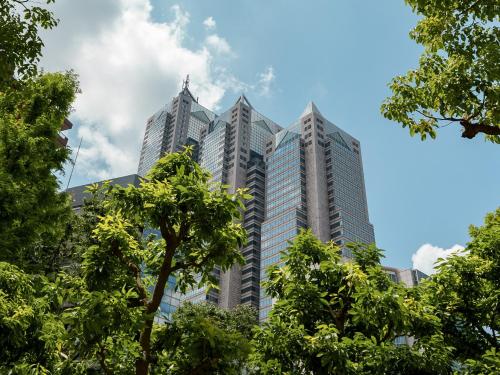 een hoog gebouw met bomen ervoor bij Park Hyatt Tokyo in Tokyo