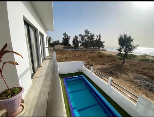 una piscina al lado de una casa con playa en pieds dans l'eau nianing, en Nianing