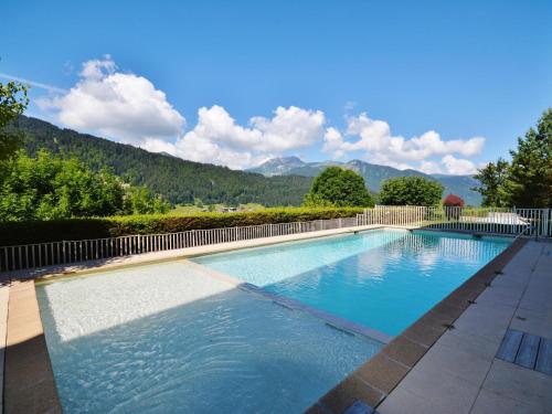une grande piscine avec des montagnes en arrière-plan dans l'établissement Appartement T3 pour 6 pers. avec piscine, parking, et balcon - Morzine - FR-1-684-48, à Morzine