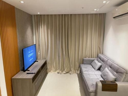 a living room with a couch and a flat screen tv at Flat Hotel Samba Barra Jeunesse Arena Projac Rio Centro in Rio de Janeiro