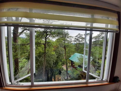 ein Fenster mit Blick auf ein Haus in der Unterkunft Relaxing / Minimalist homestay - 1 Bed & Bath in Camp John Hay