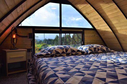 Bett in einem Zimmer mit einem großen Fenster in der Unterkunft Chalet Petit Verdot in Medellín