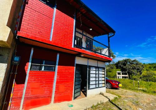 a red building with a balcony and a parking lot at Hermosa casa de campo en Barbosa in Barbosa