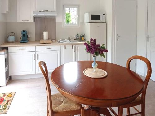 eine Küche mit einem Holztisch mit einer Vase mit Blumen darauf in der Unterkunft Studio charmant proche centre, terrasse privée, parking, 2km plage - Saint-Jean-de-Monts - FR-1-426-532 in Saint-Jean-de-Monts