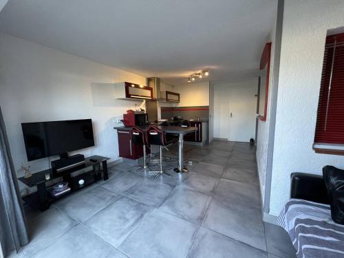 un salon avec une télévision et une table dans l'établissement Appartement Climatisé T2+Cabine, 4 Couchages, Parking, à 450m de la Plage – Port Leucate - FR-1-81-595, à Port-Leucate
