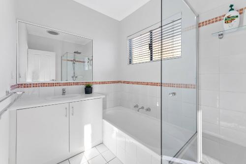 Un baño blanco con bañera, lavabo y ducha. en Modern Scarborough Townhouse, en Perth