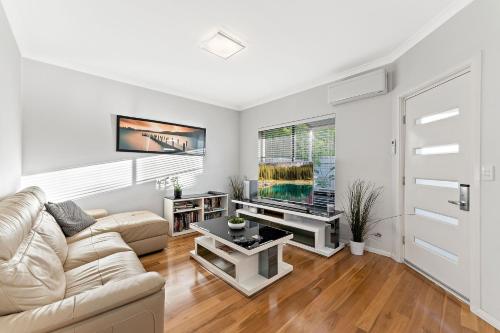 a living room with a couch and a tv at Modern Scarborough Townhouse in Perth