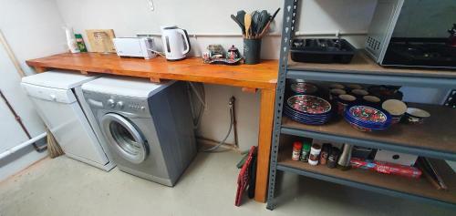a laundry room with a washing machine and a shelf at Karoo Leeu Cottage in Oudtshoorn