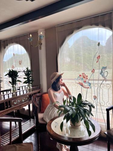 a woman sitting at a table in front of a window at Indochine Cruise Lan Ha Bay in Ha Long
