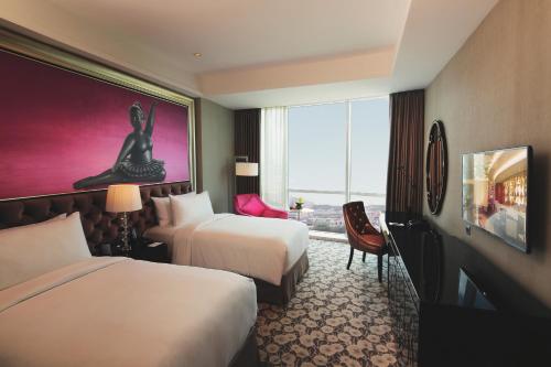 a hotel room with two beds and a window at Hotel Ciputra World Surabaya managed by Swiss-Belhotel International in Surabaya