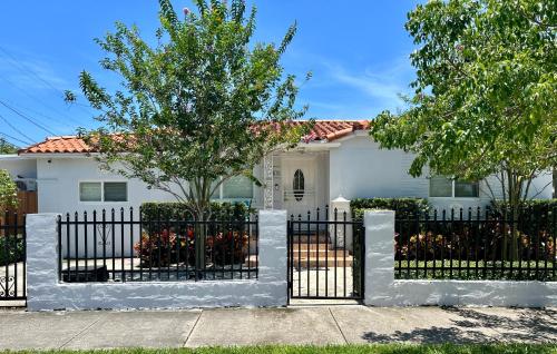 une maison blanche avec une clôture blanche dans l'établissement Main House 3 Bed 2 Bath & Guest House 1 Bed 1 Bath, à Miami