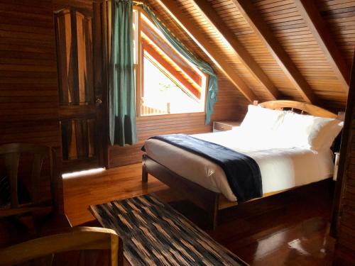 Bett in einem Holzzimmer mit Fenster in der Unterkunft Zafiro Boutique Hotel in Mindo