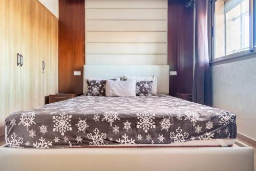 1 dormitorio con 1 cama con manta blanca y negra en Magnifique appartement Les perles de marrakech lux avec 2 piscines, en Marrakech