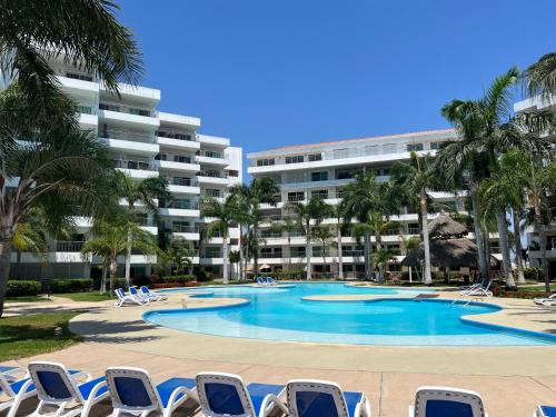 a swimming pool with chairs and a building at Departamento en Marina in Mazatlán