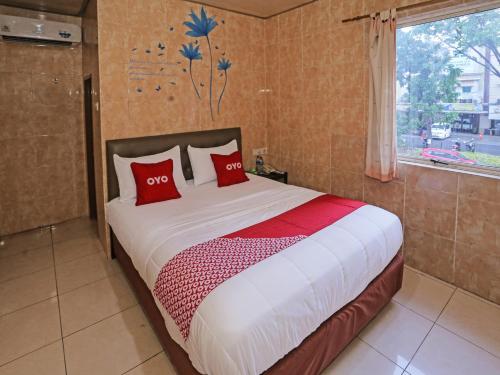 Schlafzimmer mit einem Bett mit roten Kissen und einem Fenster in der Unterkunft SUPER OYO 92672 Hotel Bsd in South Tangerang