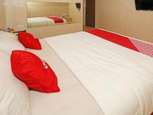 a large white bed with red pillows in a room at OYO 92674 Hotel Ciputat in South Tangerang