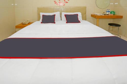 a bedroom with a large white bed with two pillows at Super OYO Capital O 92676 Hotel Sion Holiday in South Tangerang