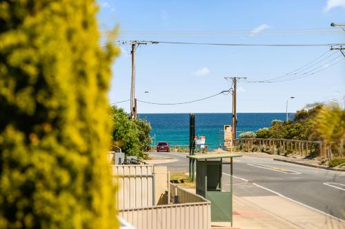 an empty street with the ocean in the background at The Love Shack - Silver Sands - C21 SouthCoast Holidays in Aldinga Beach