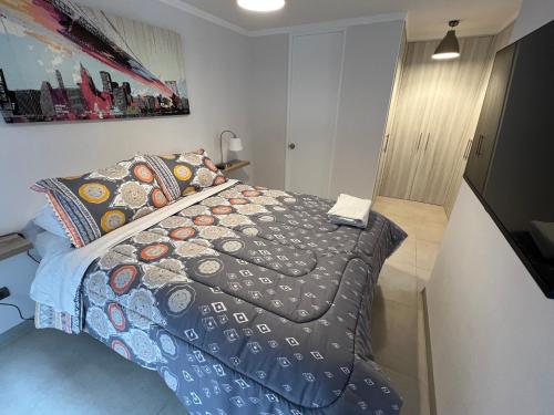 ein Schlafzimmer mit einem Bett mit einer Bettdecke und Kissen in der Unterkunft Departamento Coquimbo - La Serena in Coquimbo