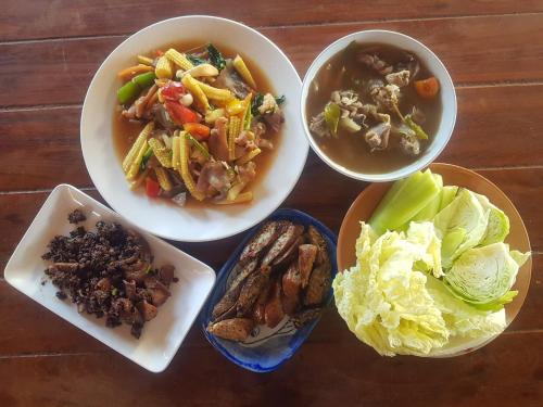 a table with bowls of food and bowls of soup at Kedthawa Homestay เฮือนเก็ดถะหวา in Ban Cho Lae