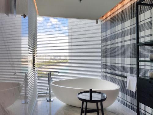 a bath tub in a bathroom with a large window at The Shanhaitian Resort Sanya, Autograph Collection in Sanya