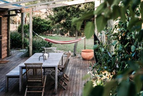 a patio with a wooden table and chairs and a hammock at Ilkley House - A Refreshing Family Rural Getaway in Mudgee