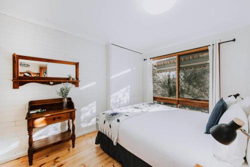 a bedroom with a bed and a desk and a window at Ilkley House - A Refreshing Family Rural Getaway in Mudgee