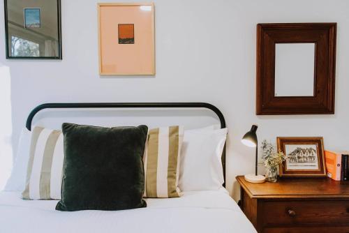 a bedroom with a bed with pillows and a mirror at Ilkley House - A Refreshing Family Rural Getaway in Mudgee