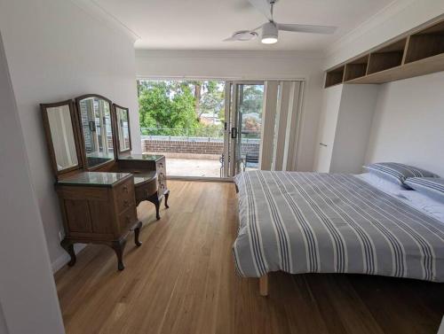 a bedroom with a bed and a dresser and a mirror at Bateau Bay Retreat in Bateau Bay