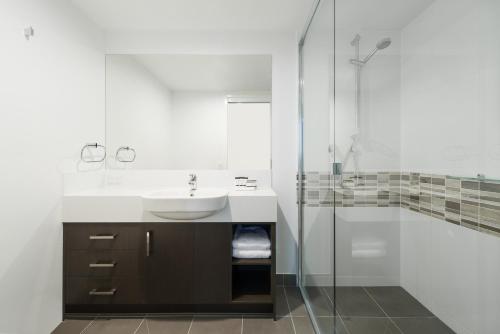 a bathroom with a sink and a glass shower at Pacific Sands Apartments Mackay in Mackay