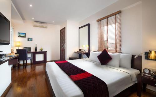 a bedroom with a large white bed with a desk and a desk at Hanoian Central Hotel & Spa in Hanoi