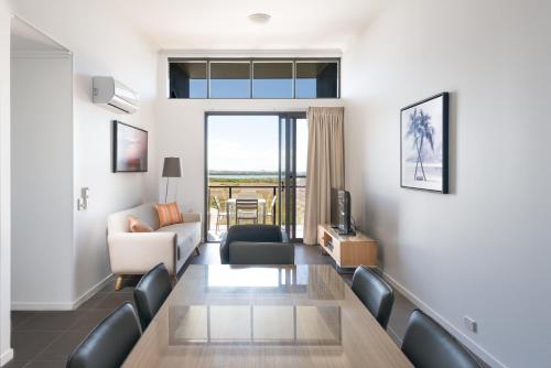 a living room with a couch and a dining room table at Pacific Sands Apartments Mackay in Mackay