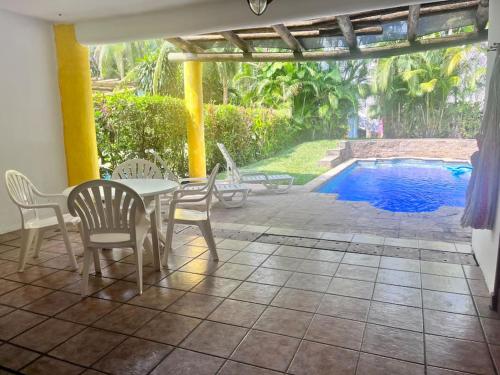 un patio con mesa y sillas y una piscina en Casa villas del pacifico en puerto San José, en Puerto San José