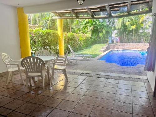 a patio with a table and chairs and a swimming pool at Casa villas del pacifico en puerto San José in Puerto San José